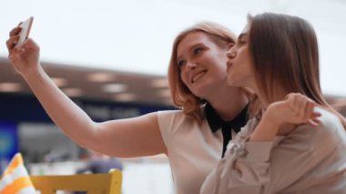 Selfie alışveriş merkezinde yapım iki mutlu genç kadın. Sevimli arkadaşlar bir selfie almak.