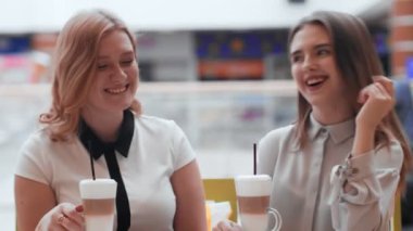 Kafede oturup kahve içen iki genç kadın..