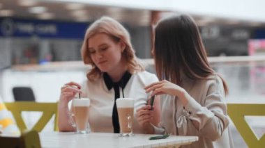 Kafede oturup kahve içen iki genç kadın..