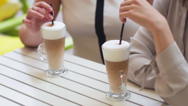 Twee jonge vrouwen die praten en koffie drinken zitten in café. — Stockvideo