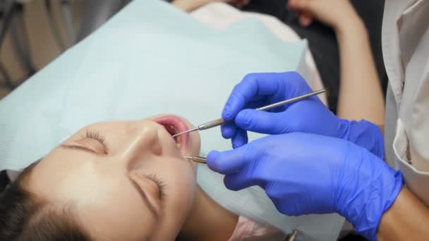 Vrouwelijk tandarts behandeling tanden aan jonge vrouw patiënt in kliniek. — Stockvideo