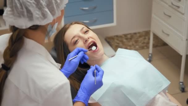 Женщина-дантист лечит зубы молодой женщине в клинике . — стоковое видео