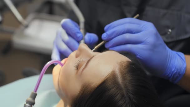 Muž zubař léčení zuby na mladou ženu pacienta na klinice. — Stock video