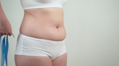 Şişman karnını ölçen şişman bir kadın..