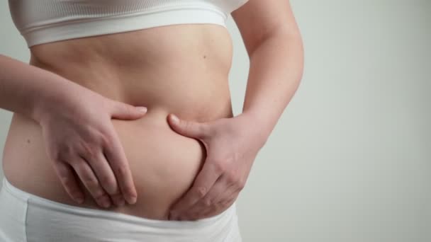 Kvinna i vita underkläder håller sin magen fett. — Stockvideo