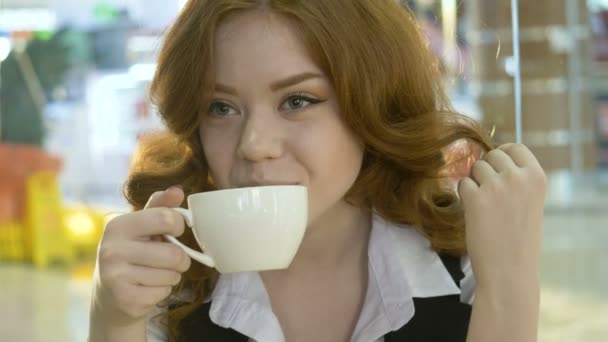 Рыжая женщина пьет капучино в кафе . — стоковое видео