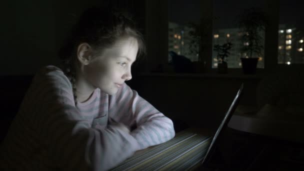 Ltttle κορίτσι ψάχνει για tablet ξαπλωμένη στο κρεβάτι τη νύχτα. — Αρχείο Βίντεο