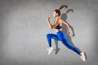 Sportif genç atletik kadın runing ve atlama.