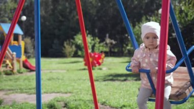 Sevimli küçük kız yaz parkta salıncak üzerinde.