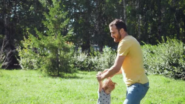 Joven padre girar su pequeña hija al aire libre . — Vídeos de Stock