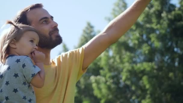 Junger Vater zeigt und erklärt seine kleine Tochter. — Stockvideo