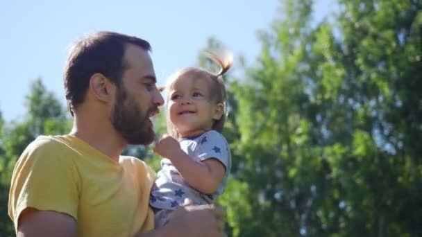 Jonge vader spelen en overgeven zijn kleine dochter buitenshuis. — Stockvideo