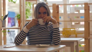 Gülümseyen ve kafede kahve içme genç düşünceli kadın.