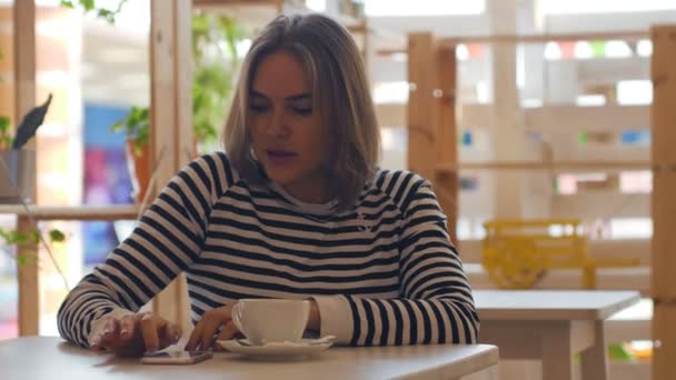 Hermosa mujer usando teléfono inteligente en la cafetería . — Vídeo de stock