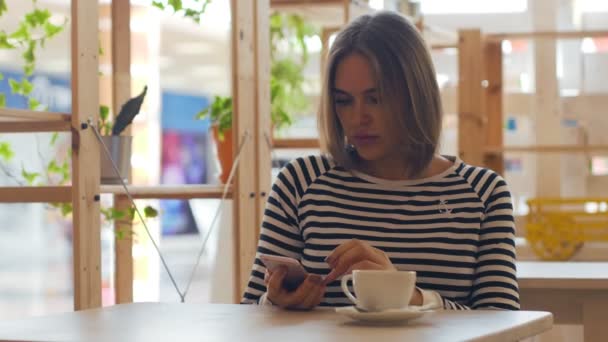 Hermosa mujer usando teléfono inteligente en la cafetería . — Vídeos de Stock