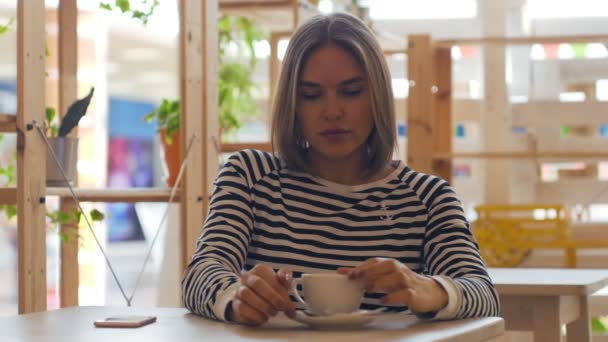 Joven mujer reflexiva sonriendo y tomando café en la cafetería . — Vídeos de Stock