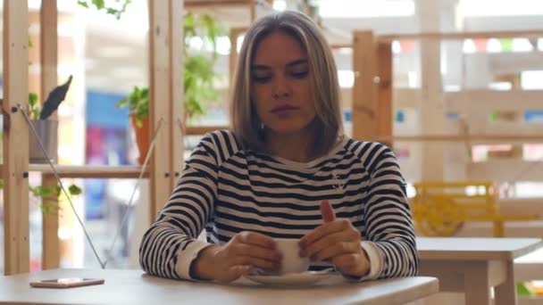 Joven mujer reflexiva sonriendo y tomando café en la cafetería . — Vídeos de Stock