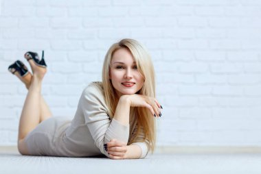 Şehvetli kadın kat beyaz tuğla duvarın üzerinde yalan.