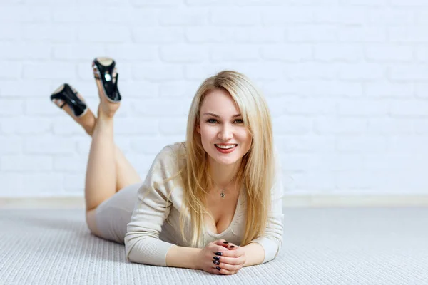 Sensuele vrouw liggend op de vloer tegen witte bakstenen muur. — Stockfoto