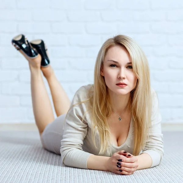 Femme sensuelle couchée sur le sol contre un mur de briques blanches . — Photo