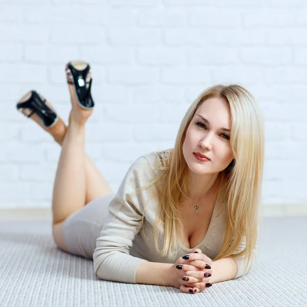 Sensual woman lying on floor against white brick wall. — Stock Photo, Image