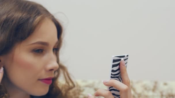 Молодая женщина смотрит в зеркало и проверяет свой макияж . — стоковое видео