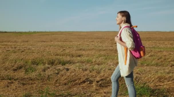 Молода жінка з рожевим рюкзаком ходить — стокове відео