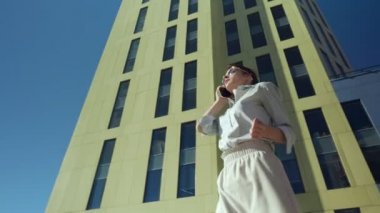 İş merkezine yakın yürürken telefonda konuşurken iş kadını.