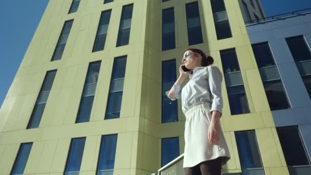 Biznes kobieta rozmawia przez telefon podczas spaceru w pobliżu centrum biznesowego. — Wideo stockowe