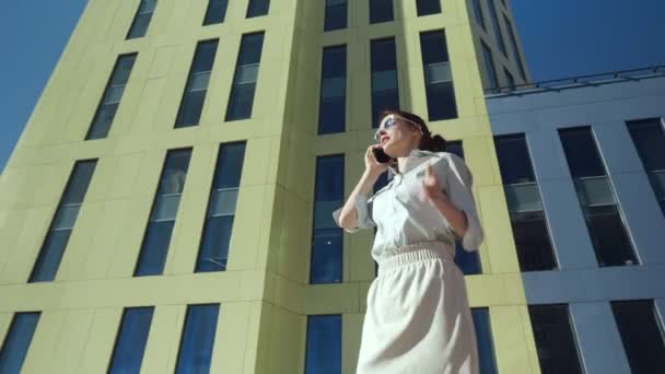Affärskvinna som pratar i telefonen medan du går nära Businesscenter. — Stockvideo