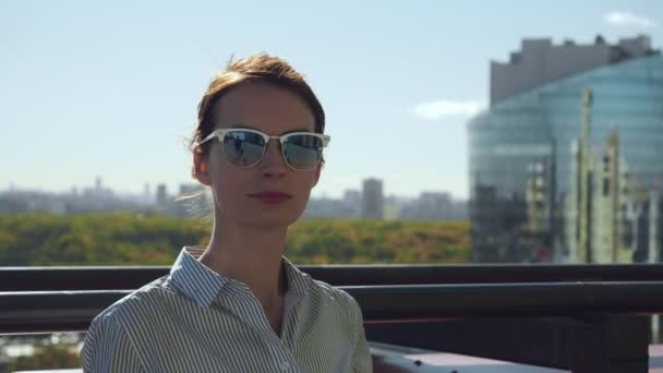 Young woman in sunglasses posing on commercial building balcony. — Stock Video