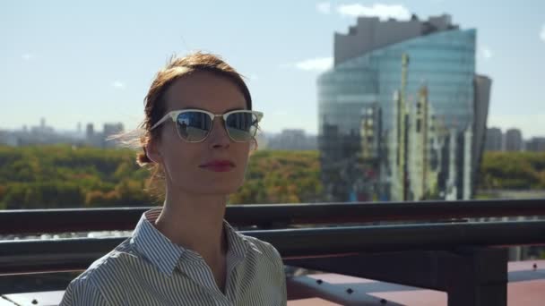 Young woman in sunglasses posing on commercial building balcony. — Stock Video