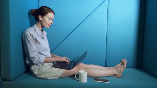 Деловая женщина сидит на диване и работает за ноутбуком . — стоковое видео