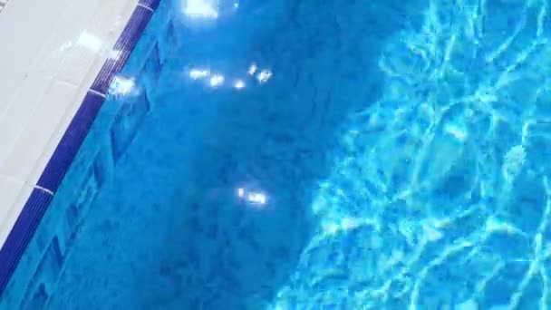 Zvlnění na modrou vodu v bazénu s odrazy světla. — Stock video