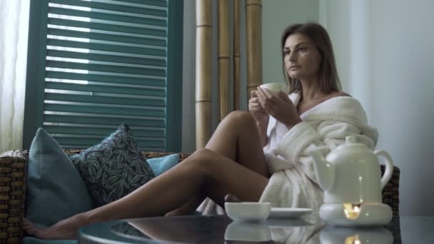 Mujer en albornoz bebiendo té en el salón de spa . — Vídeo de stock