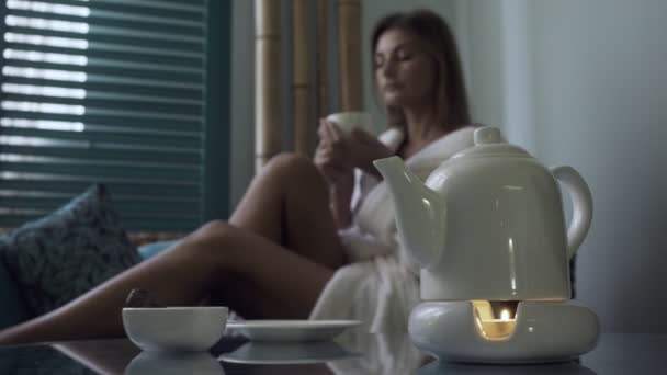 Woman in bathrobe drinking tea in spa salon. — Stock Video