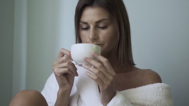 Mujer en albornoz bebiendo té en el salón de spa . — Vídeo de stock