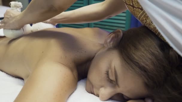 Kvinna får massage med heta växtbaserade väskor. — Stockvideo