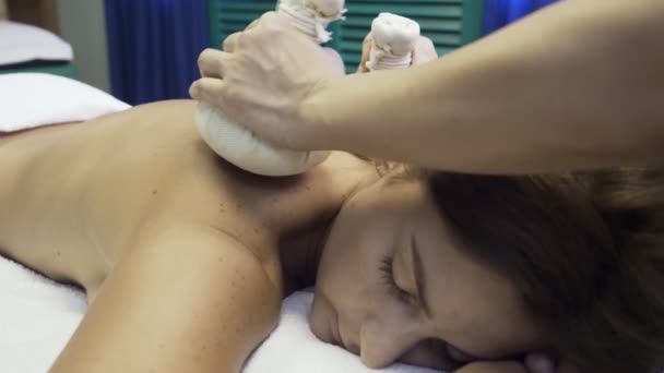 Frau bekommt Massage mit heißen Kräutertüten. — Stockvideo