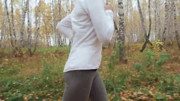 Mujer rubia joven corriendo en el parque de otoño . — Vídeos de Stock