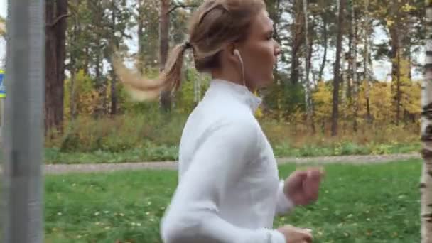 Joven mujer deportiva corriendo en el parque de otoño . — Vídeos de Stock