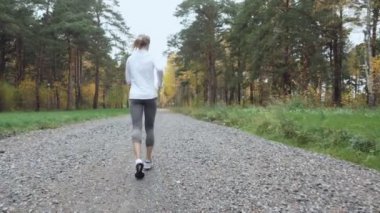 Sonbahar parkta çalışan sarışın genç kadın.