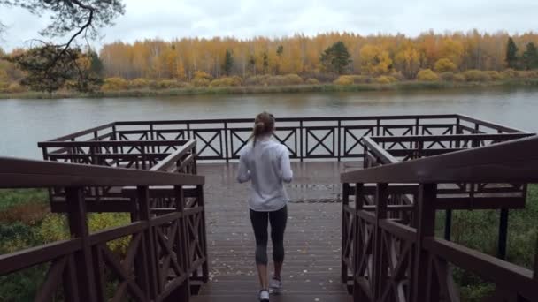 Deportiva mujer se calienta antes de correr en el muelle de madera . — Vídeos de Stock