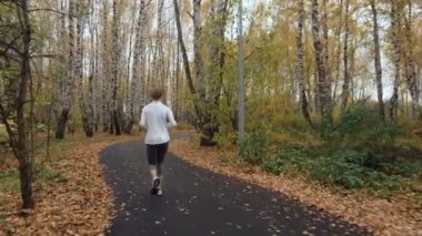 Sonbahar parkta çalışan genç sportif kadın.