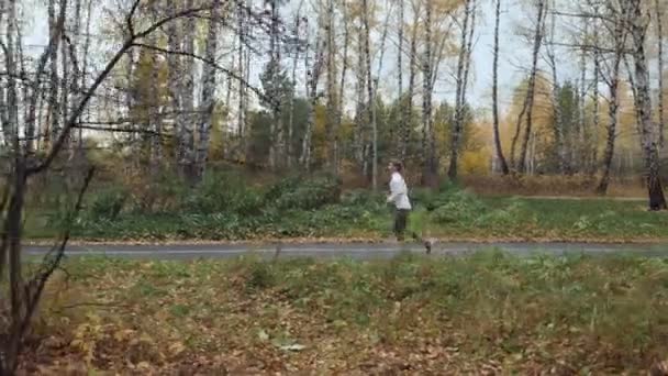 Молодая блондинка бегает в осеннем парке . — стоковое видео