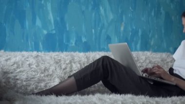 Odasında kanepede otururken dizüstü bilgisayar üzerinde çalışan kadın.