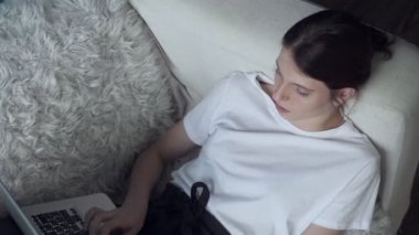 Evde kanepede döşenmesi sırasında dizüstü bilgisayarda çalışan kadın.