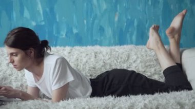 Odasında kanepede döşenmesi sırasında dizüstü bilgisayar üzerinde çalışan kadın.