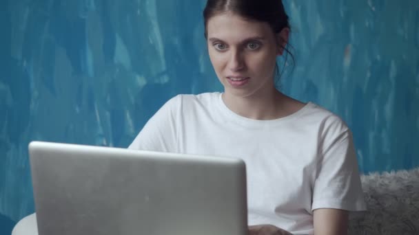 Mulher trabalhando no computador portátil enquanto sentado no sofá no quarto . — Vídeo de Stock