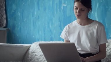 Evde dizüstü bilgisayar üzerinde çalışan serbest meslek sahibi kadın.